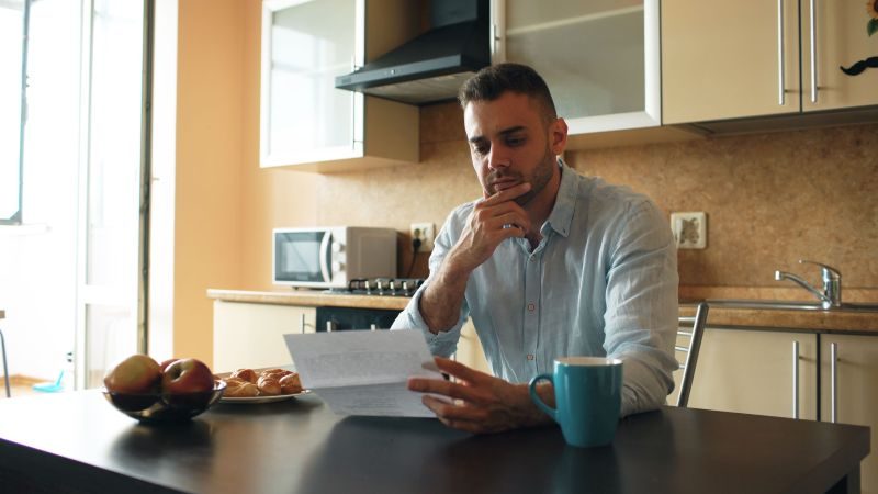 Person at a kitchen table reading a CRA letter with a worried look